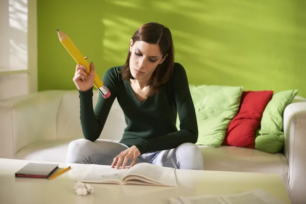 Studente donna che fa i compiti a casa con grande matita — Foto Stock