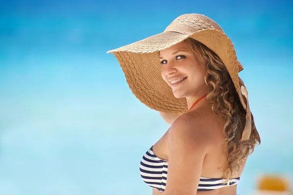 Portret van vrouw met stro hoed op strand glimlachen — Stockfoto