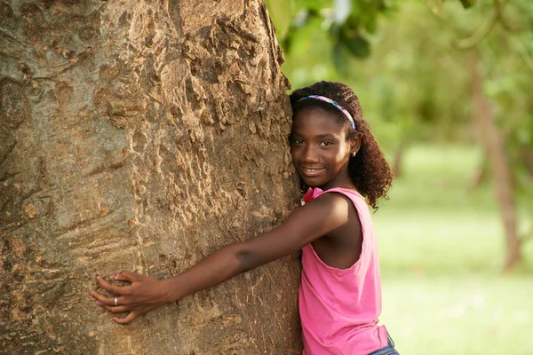 Retrato de niña negra ecologista abrazando el árbol y sonriendo —  Fotos de Stock