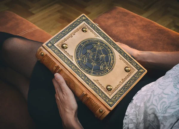 Zengin süslü deri kitap bir kızın ellerinde.