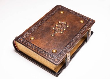 Üzerinde yaldızlı sembol bulunan antika kahverengi deri kitap izole bir şekilde yatıyordu.