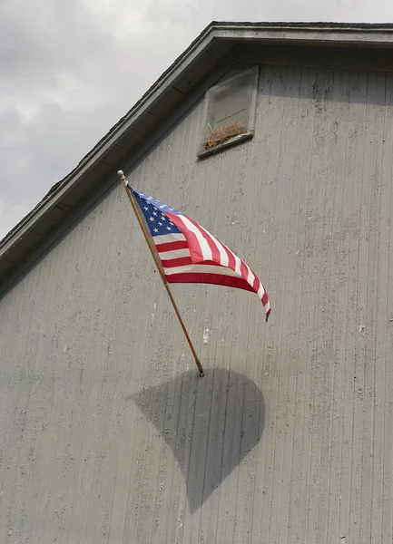 風に乗って灰色の納屋を飛ぶアメリカ国旗 — ストック写真