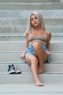 Sarışın bir model şehir ortamında poz veriyor.