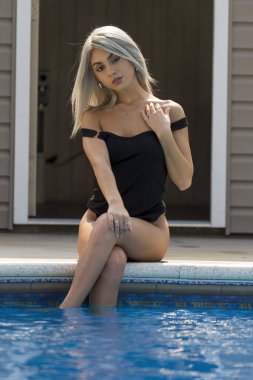 Sarışın bir bikini mankeni, yaz günlerinde havuzda eğlenir.