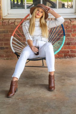 Sonbahar kıyafetleriyle dışarıda poz veren güzel bir sarışın manken.