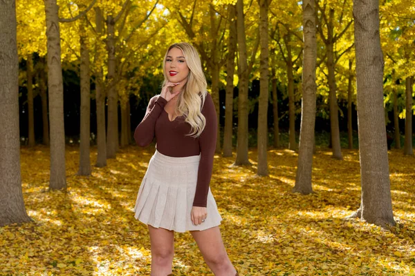 Güz havasının tadını çıkarırken dışarıda poz veren muhteşem bir sarışın model.