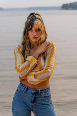 Muhteşem bir esmer model göl kenarındaki yaz havasının tadını çıkarıyor.