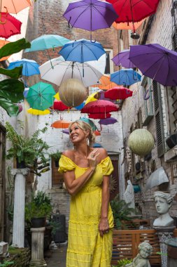 Çok sayıda renkli şemsiyenin altında muhteşem bir sarışın model poz veriyor.