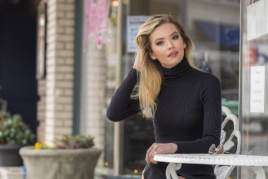 Güz havasının tadını çıkarırken dışarıda poz veren muhteşem bir sarışın model.