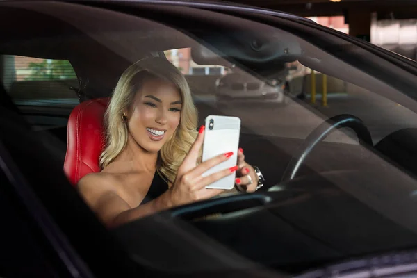 豪華なブロンドモデルは 彼女のスポーツカーを運転する前に彼女の携帯電話で話します — ストック写真