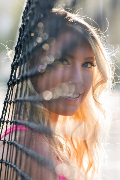 一位漂亮的金发模特在下午的阳光下在网球场打网球 — 图库照片