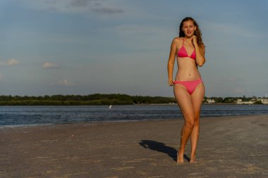 Güzel sarışın bir bikini mankeni sahilde açık havanın tadını çıkarıyor.