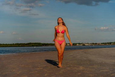 Güzel sarışın bir bikini mankeni sahilde açık havanın tadını çıkarıyor.