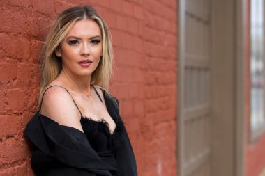 Güz havasının tadını çıkarırken dışarıda poz veren muhteşem bir sarışın model.