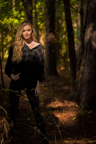 Muhteşem sarışın bir model, kasvetli bir orman ortamında poz veriyor.