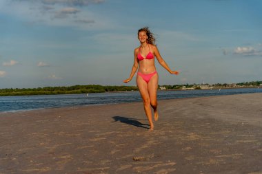 Güzel sarışın bir bikini mankeni sahilde açık havanın tadını çıkarıyor.