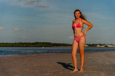 Güzel sarışın bir bikini mankeni sahilde açık havanın tadını çıkarıyor.