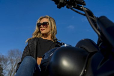 Muhteşem sarışın bir model motosikletini sürerken açık havada eğleniyor.. 