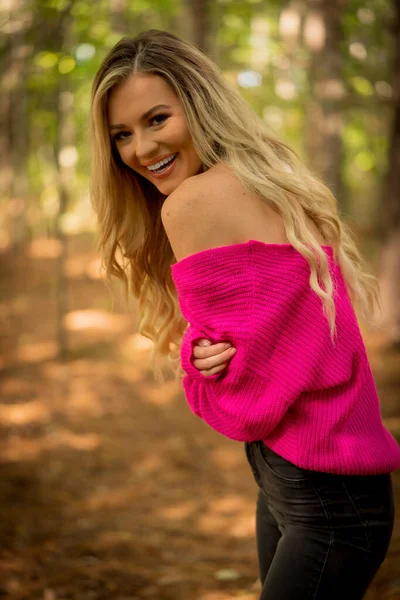 Muhteşem sarışın bir model, kasvetli bir orman ortamında poz veriyor.