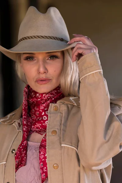 Kovboy gibi giyinmiş muhteşem sarışın bir manken. Açık havanın tadını çıkarıyor.