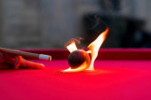 Kulečníkové koule jsou fotografovány v ohni, zatímco sedí venku v otevřeném prostředí
