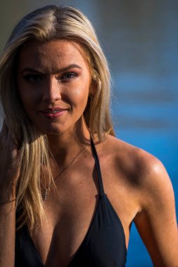 Muhteşem sarışın bir bikini modeli göl kenarında poz verirken yaz havasının tadını çıkarıyor..