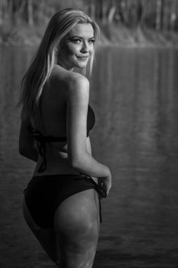 Muhteşem sarışın bir bikini modeli göl kenarında poz verirken yaz havasının tadını çıkarıyor..