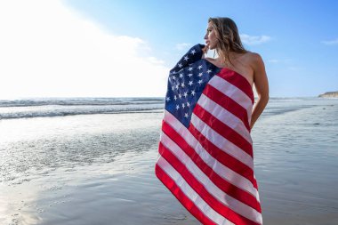 Muhteşem bir esmer model, kumsalda Amerikan bayrağıyla çıplak poz veriyor. 