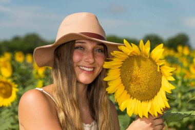Sarışın bir model, ayçiçeği tarlasında poz veriyor.