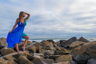 Güzel bir esmer İspanyol manken gün batımında sahilde poz veriyor.