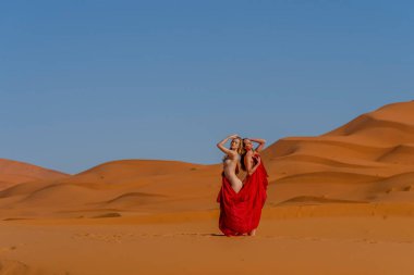 Güzel bir model, Fas 'taki büyük Sahra Çölü' ndeki kum tepelerine çıplak poz veriyor.