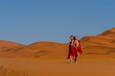 Güzel bir model, Fas 'taki büyük Sahra Çölü' ndeki kum tepelerine çıplak poz veriyor.