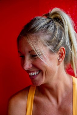 A gorgeous blonde model enjoys a day at home against a red wall before heading to work
