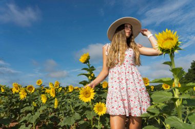 Sarışın bir model, ayçiçeği tarlasında poz veriyor.
