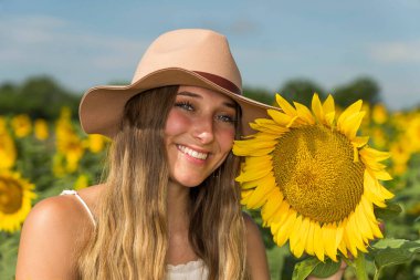 Sarışın bir model, ayçiçeği tarlasında poz veriyor.