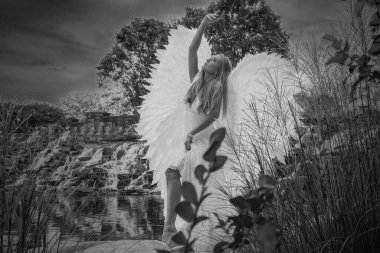 Cadılar bayramı için beyaz kanat takan güzel bir sarışın model dışarıda poz veriyor.. 