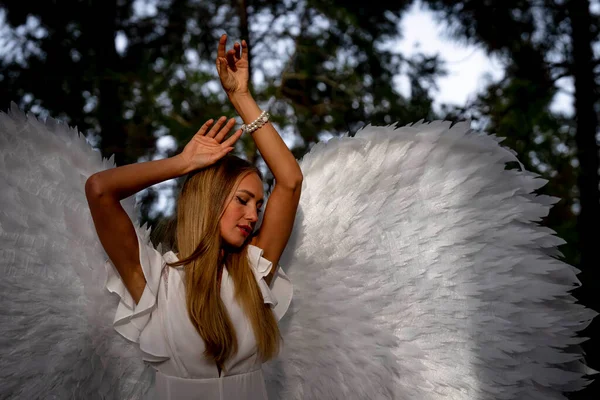 一个漂亮的金发模特穿着一套白色的翅膀在户外摆姿势 — 图库照片