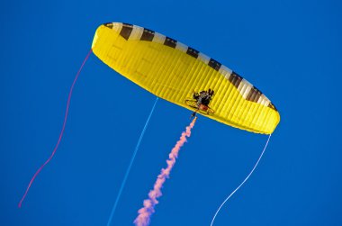 Motorized hang-glider in blue sky. clipart