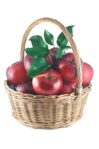 Красные яблоки с зелеными листьями в плетеной корзине — стоковое фото