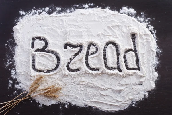 The inscription of the hands on the flour on a dark background, decorating spikelets of wheat. advertising sign — Stock Photo, Image