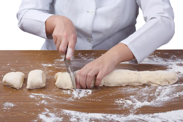 Baker skär remsor degen i delar på en mjölad planka — Stockfoto