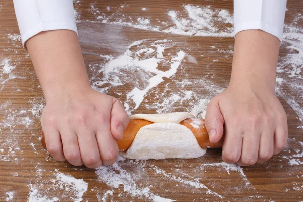 Baker rolls out the dough on a wooden kitchen table — Stock Photo, Image