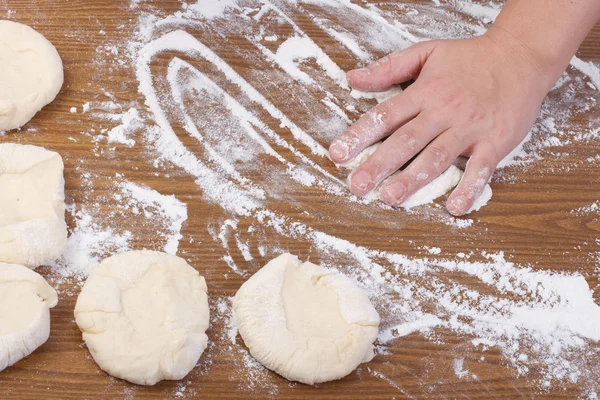 Hand gießt Mehl auf den Tisch, um Teig auszurollen — Stockfoto