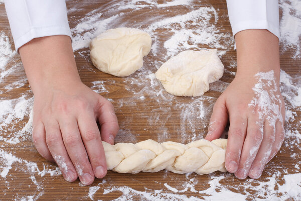 Baker's hands weave bread dough