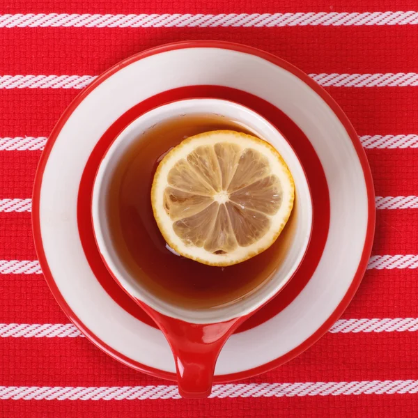 Лимонный чай вид сверху. красная чашка на полосатой скатерти — стоковое фото
