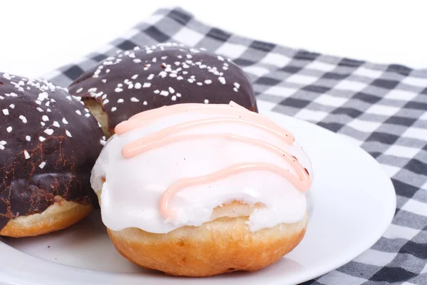 Three delicious fresh donuts in the glaze on a napkin — Stock Photo, Image