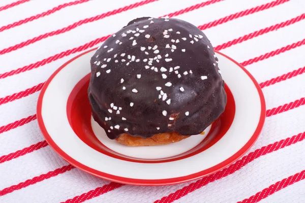 Chocolate donut on a plate against a striped tablecloth — Stock Photo, Image