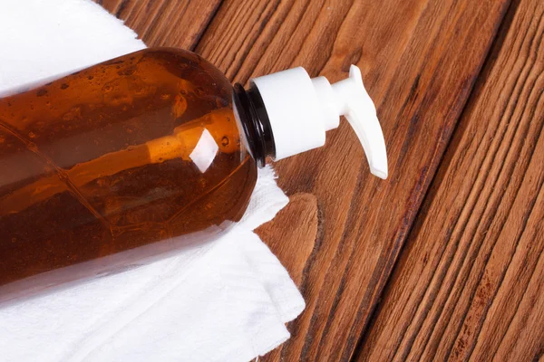 Liquid soap dispenser and a white towel on a wooden table — Stock Photo, Image