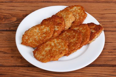 ahşap bir masa üzerinde beyaz bir plaka üzerinde patates pancakes
