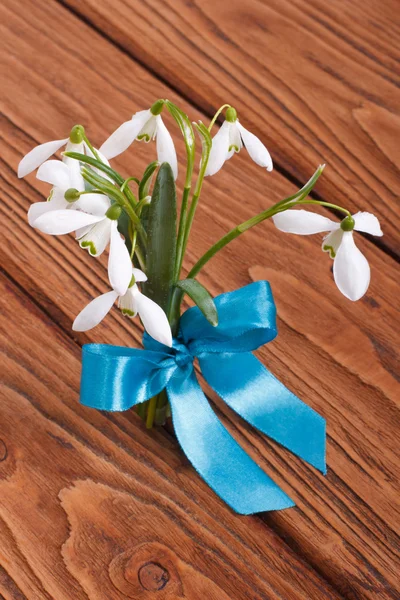 Csokor hóvirág kötve a Kékszalag egy fából készült asztal — Stock Fotó